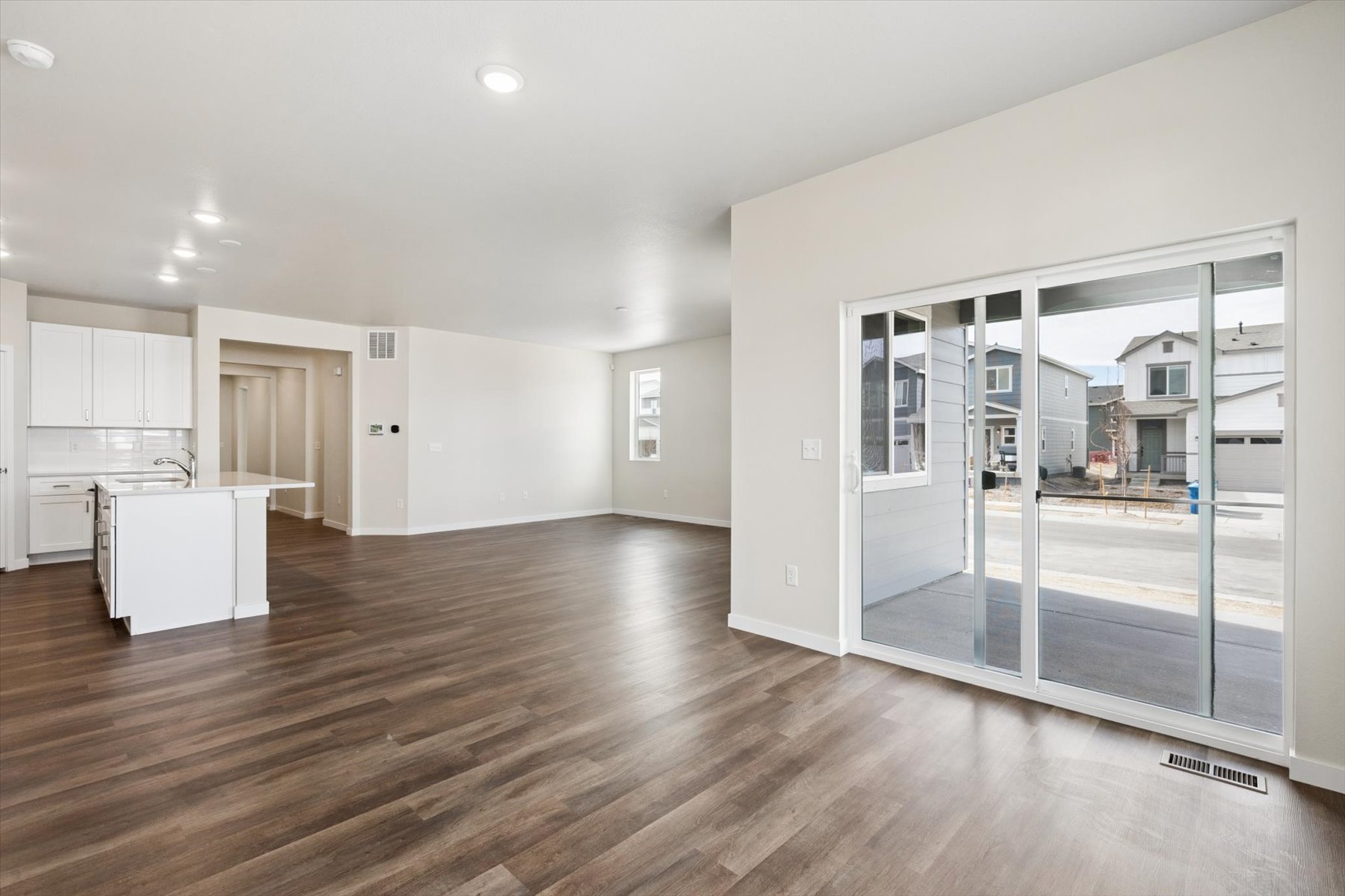 A large empty room with a glass door and a wood floor.