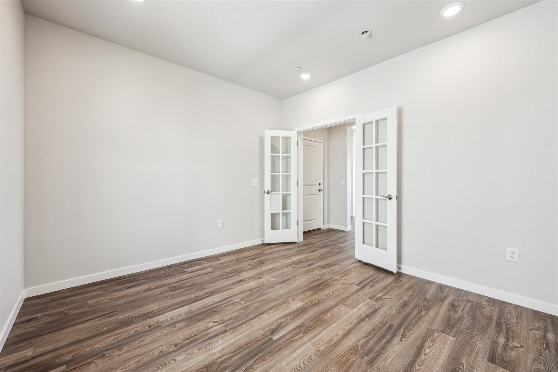 A room with white walls and wood floors.