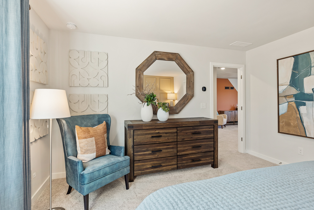 A bedroom with a mirror and a chair.