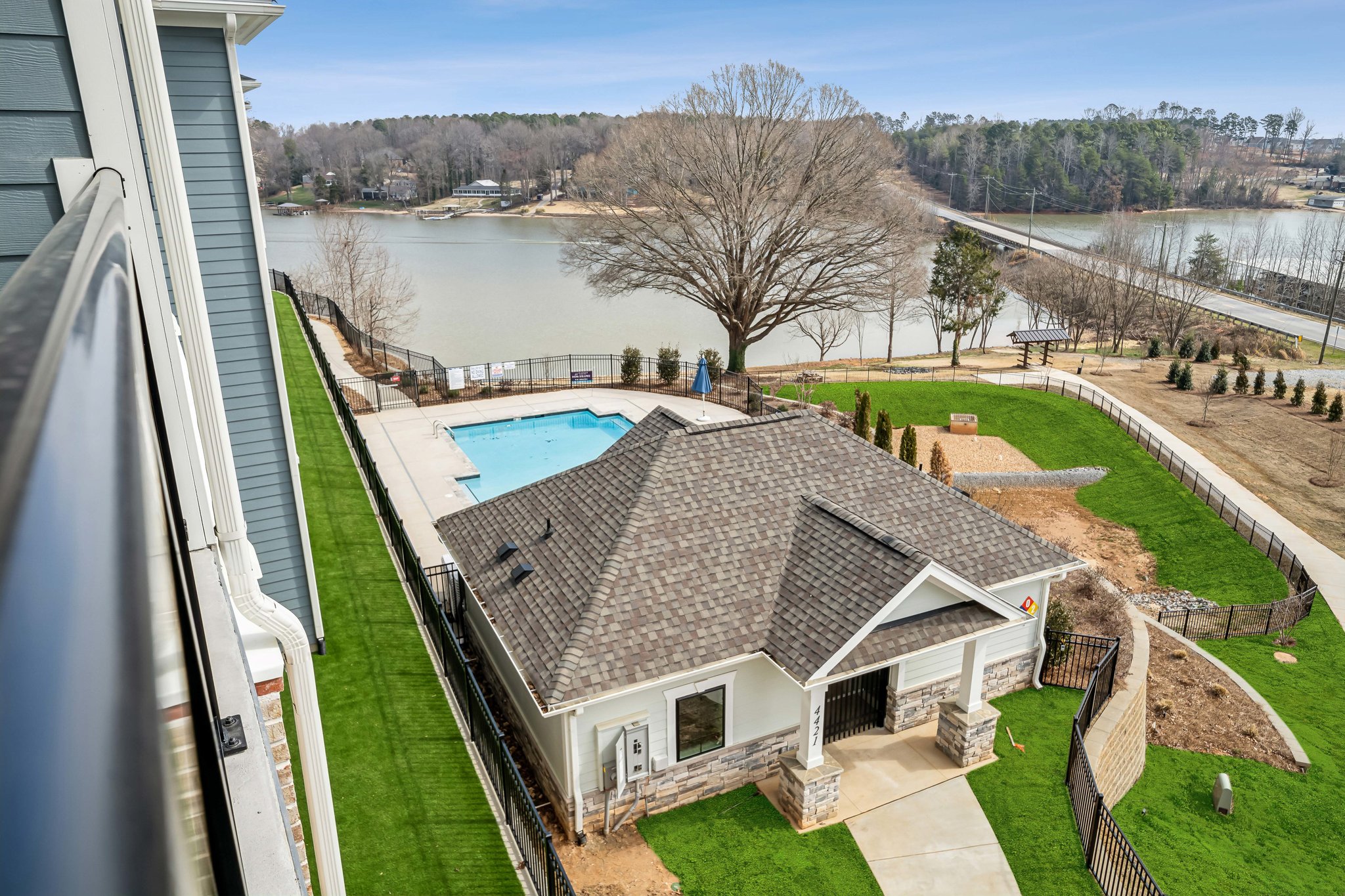 A house with a pool and a large yard with a body of water in the background.