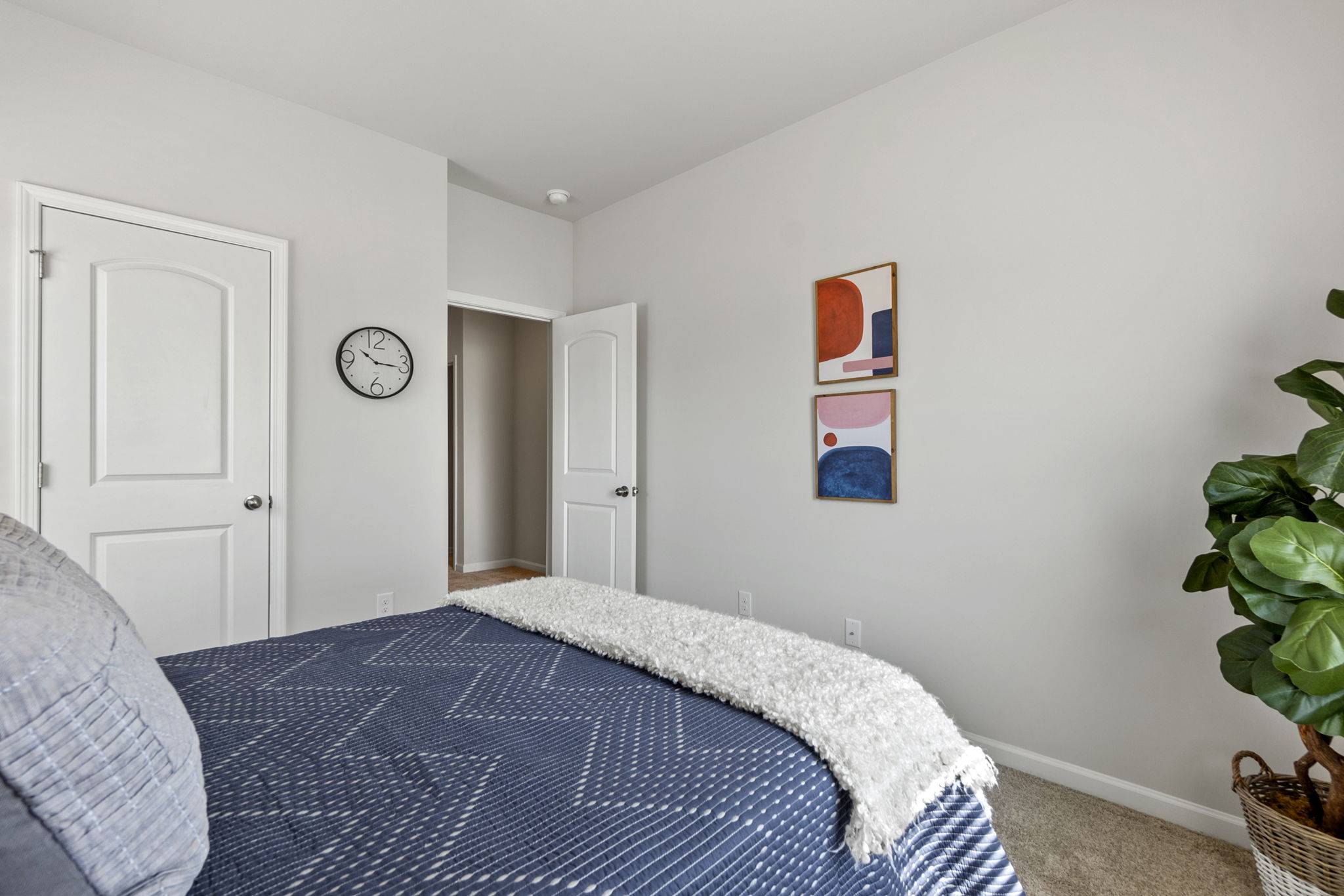 A bedroom with a bed and a clock.