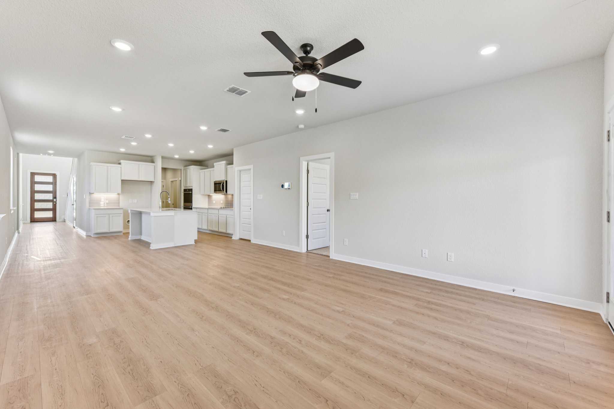 A large empty room with a wood floor and a ceiling fan.