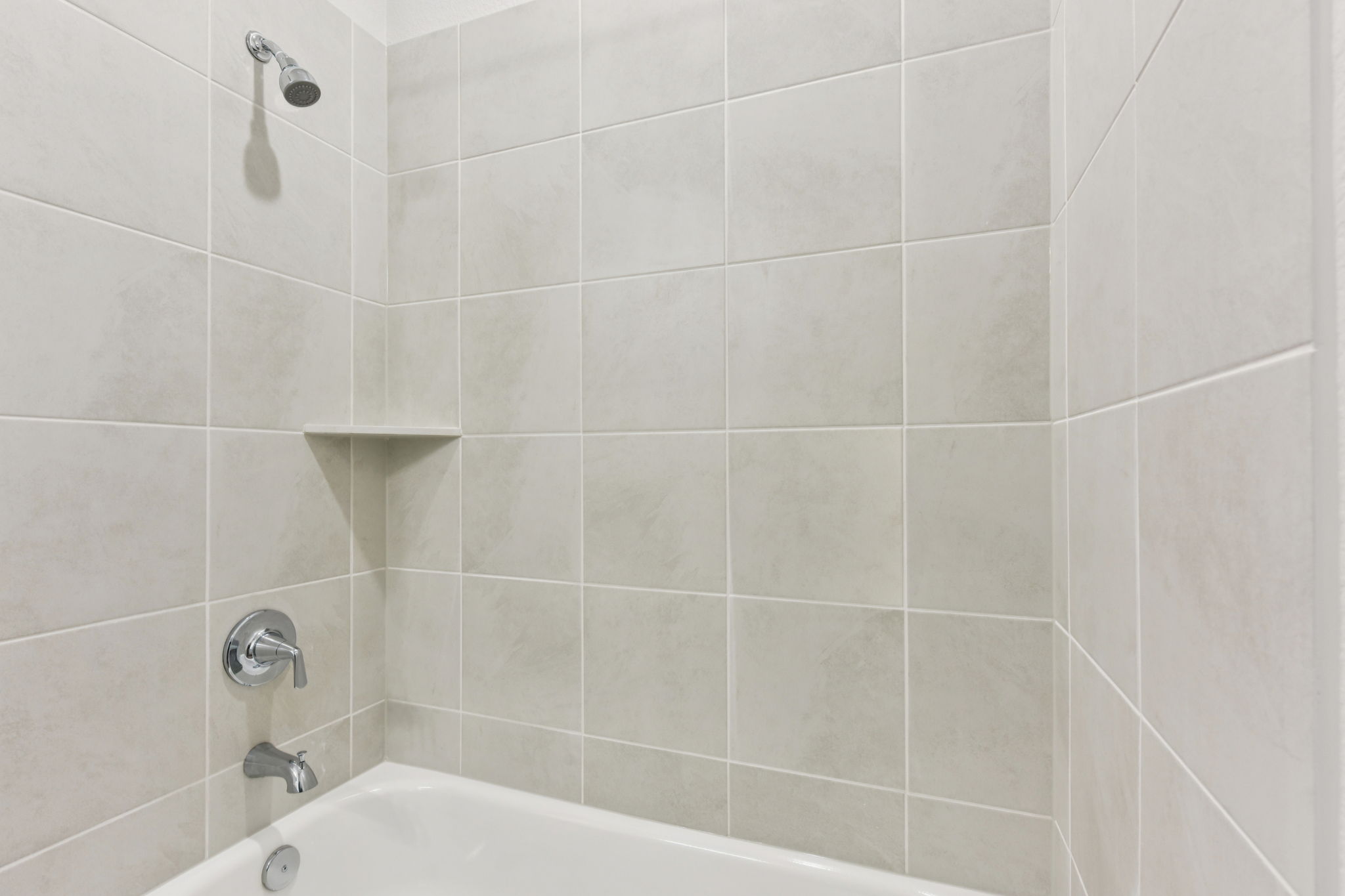 A bathtub with a tile wall.
