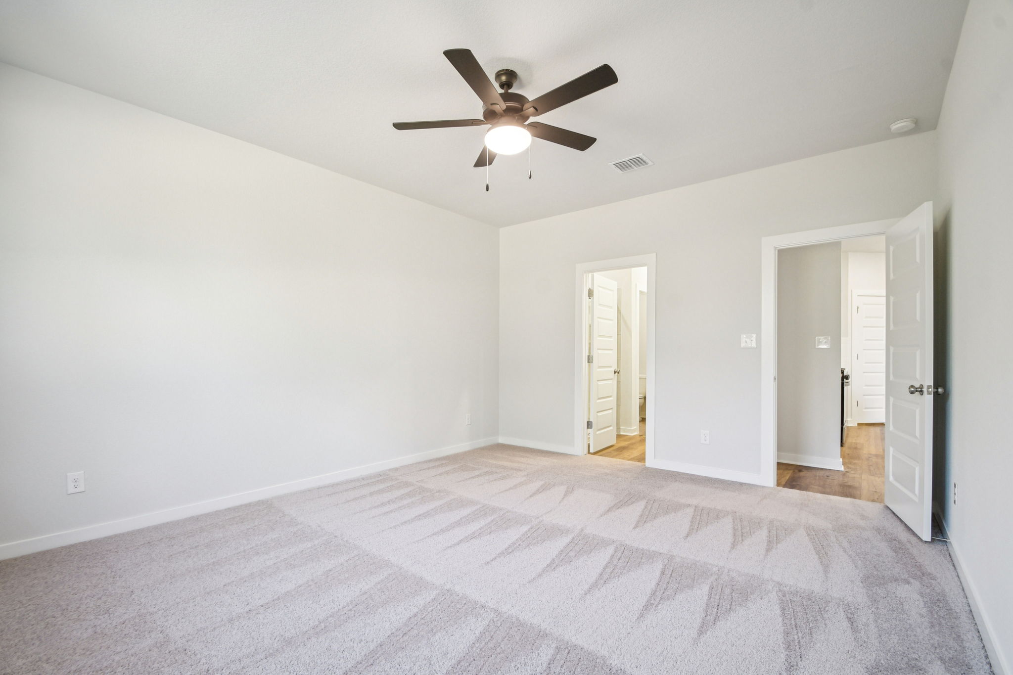 A room with a bed and a ceiling fan.