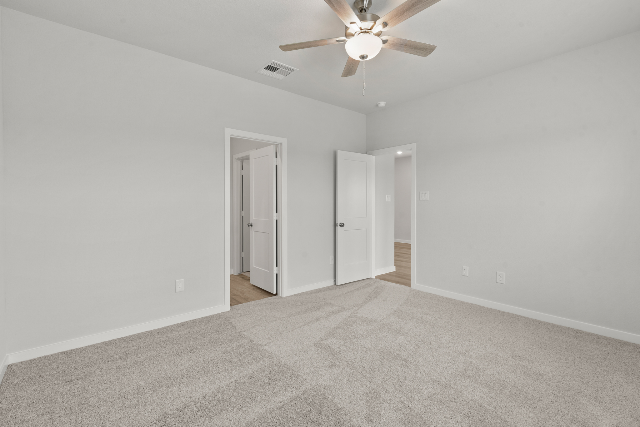A room with a ceiling fan and a carpet.