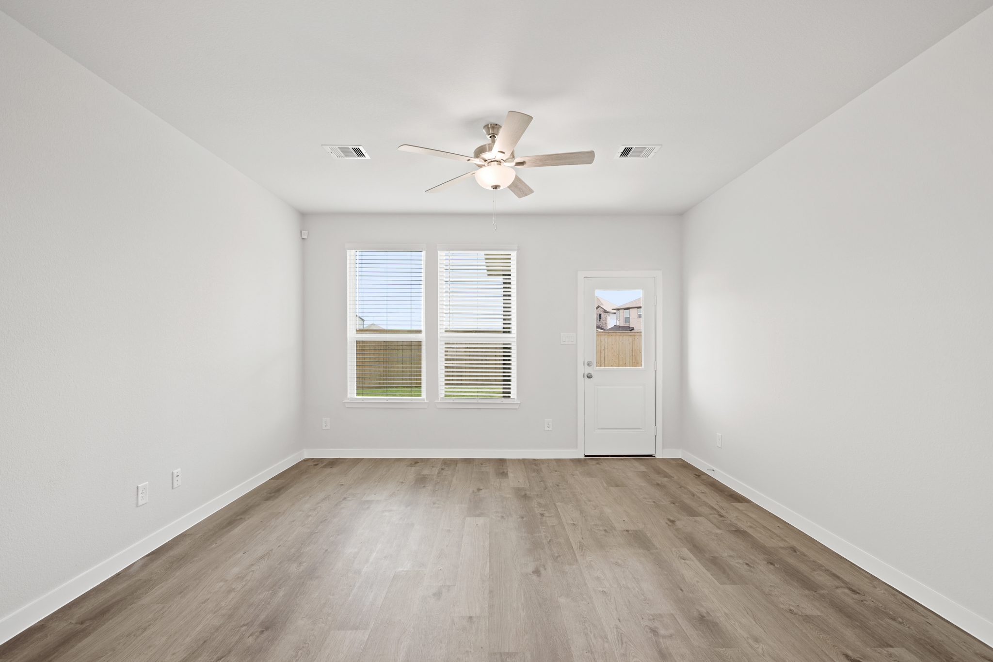 A room with a ceiling fan and a wood floor.