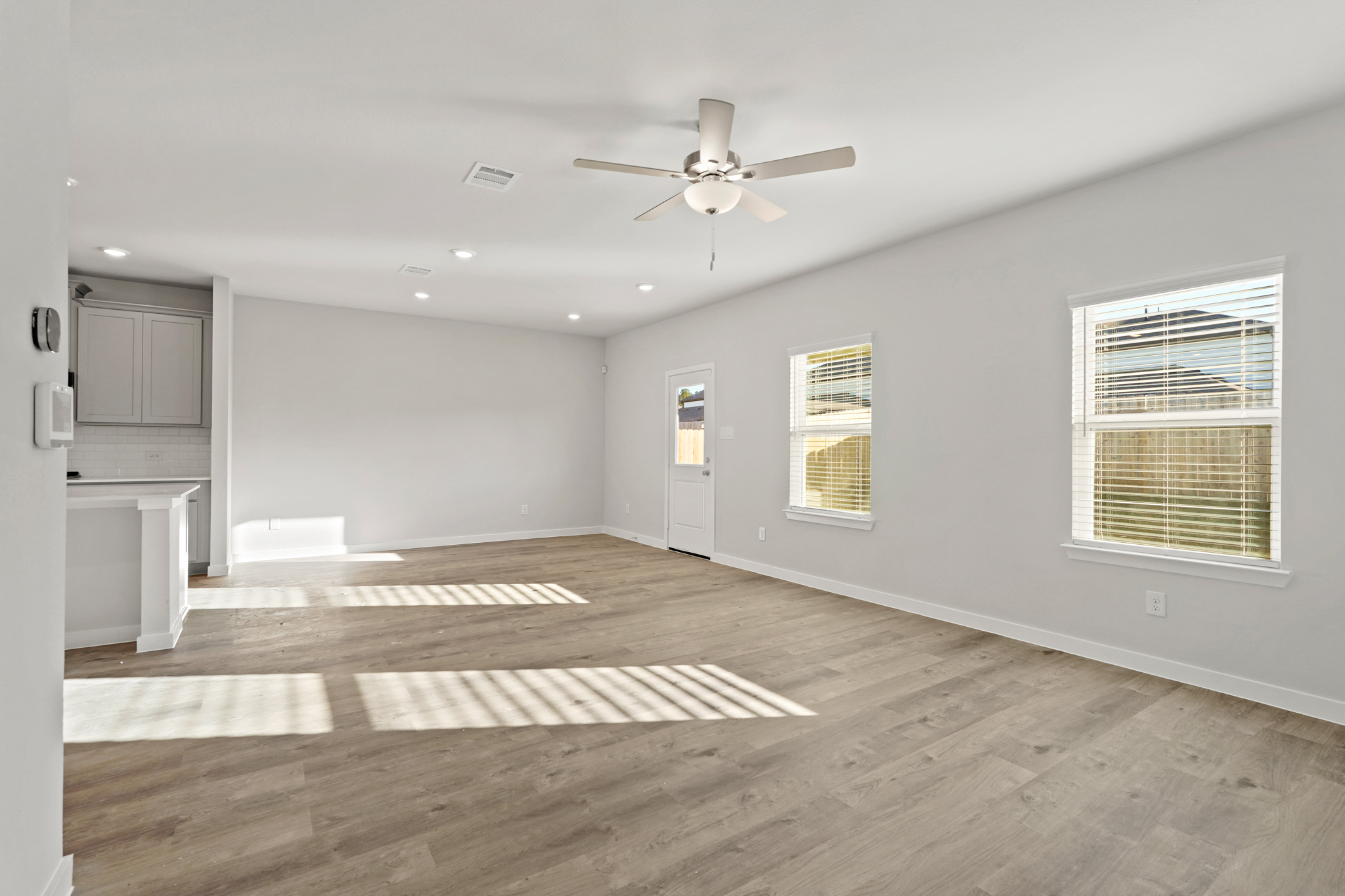 A large empty room with a wood floor and a ceiling fan.