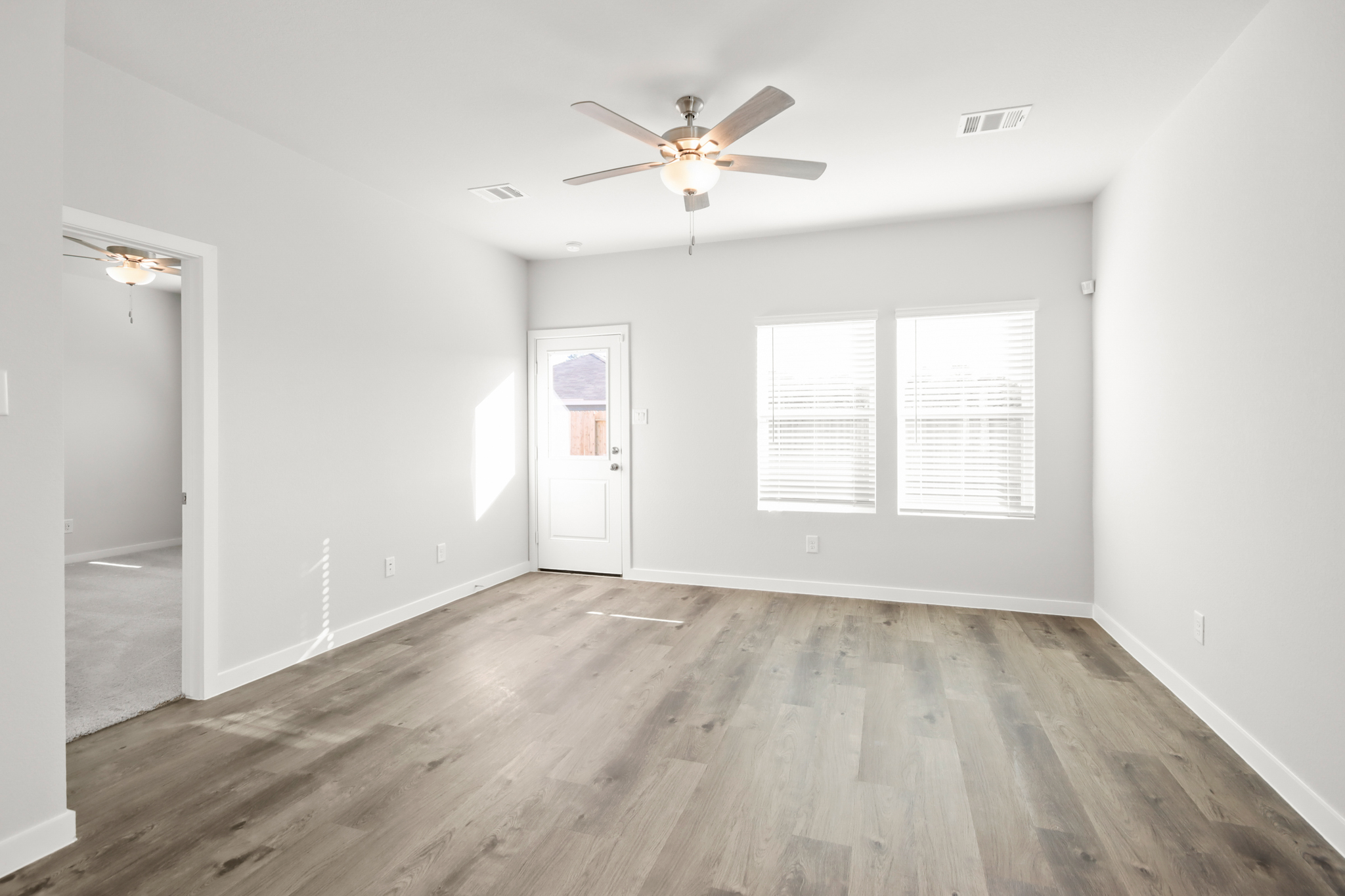 A room with a ceiling fan and a wood floor.