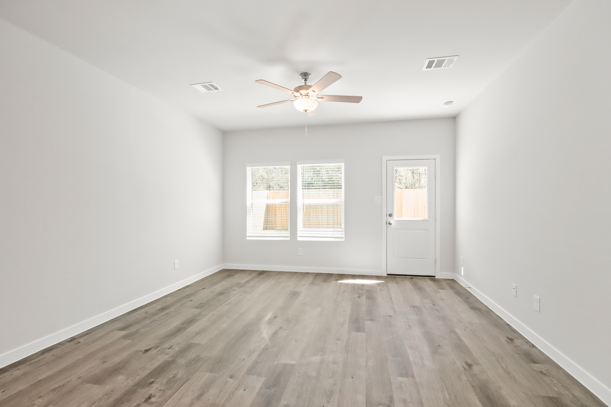 A room with a ceiling fan and a wood floor.