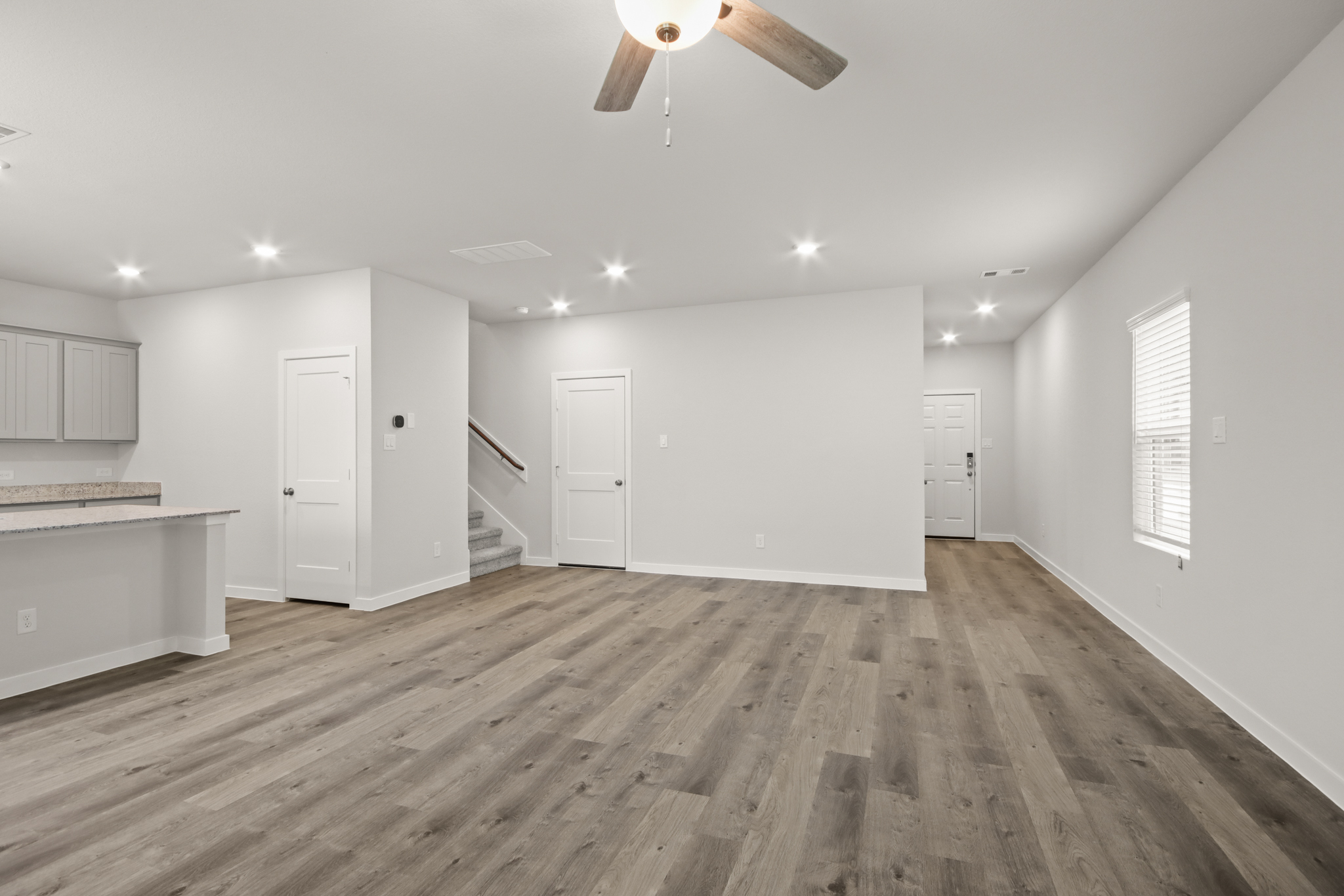 A room with white cabinets and a wood floor.
