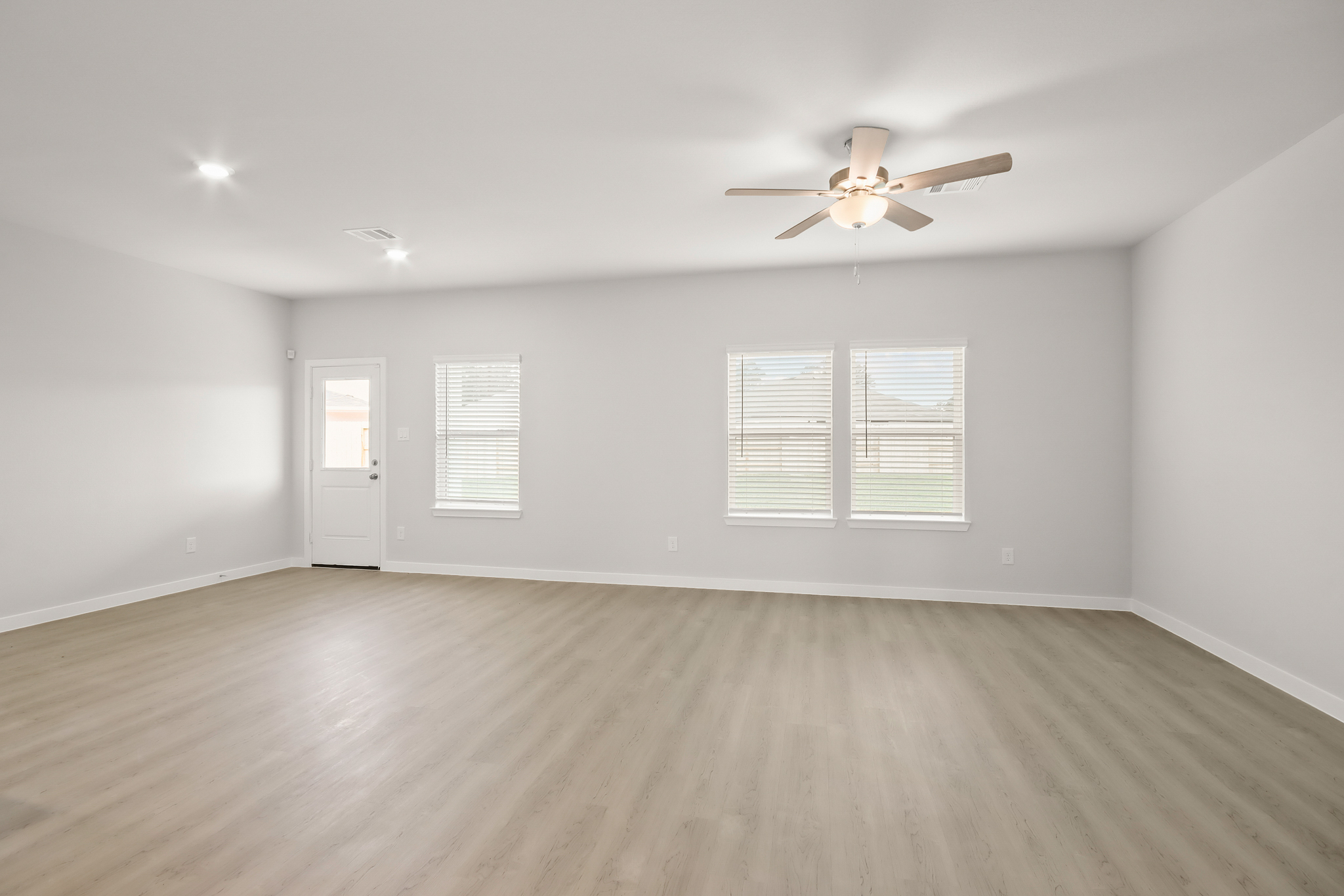 A room with a ceiling fan and a wood floor.