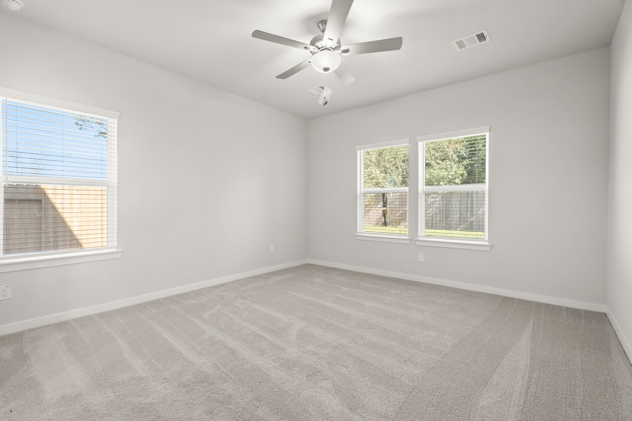 A room with a ceiling fan and windows.