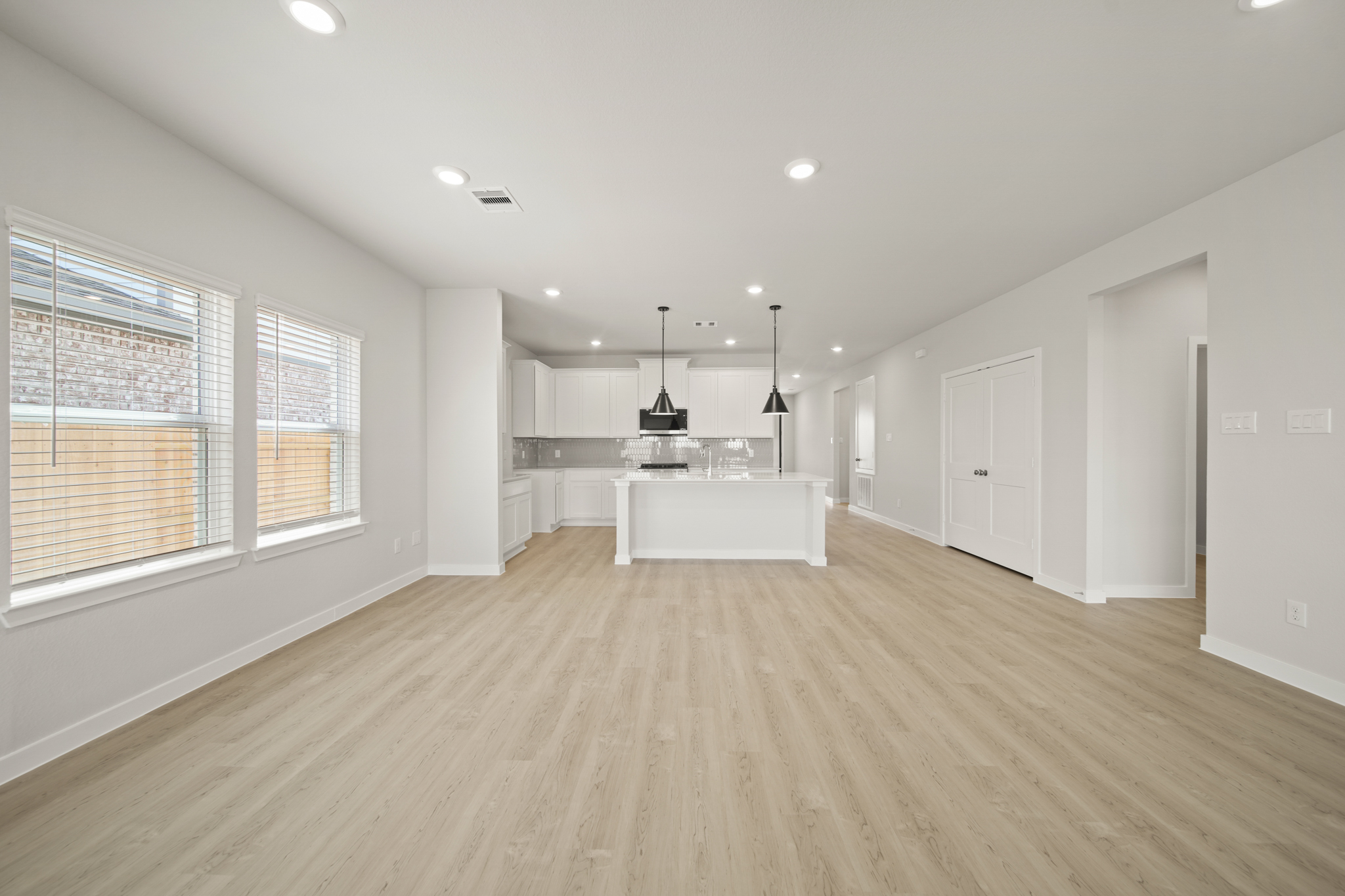 A large empty room with a wood floor and a white counter.