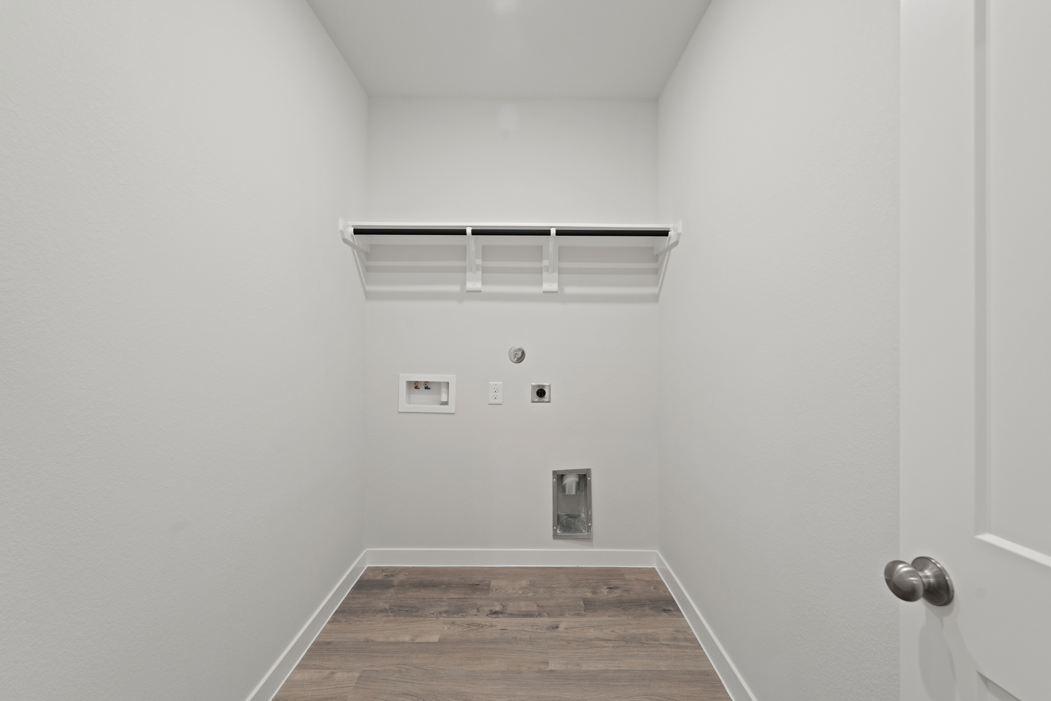 A room with a wood floor and a white wall with a light.