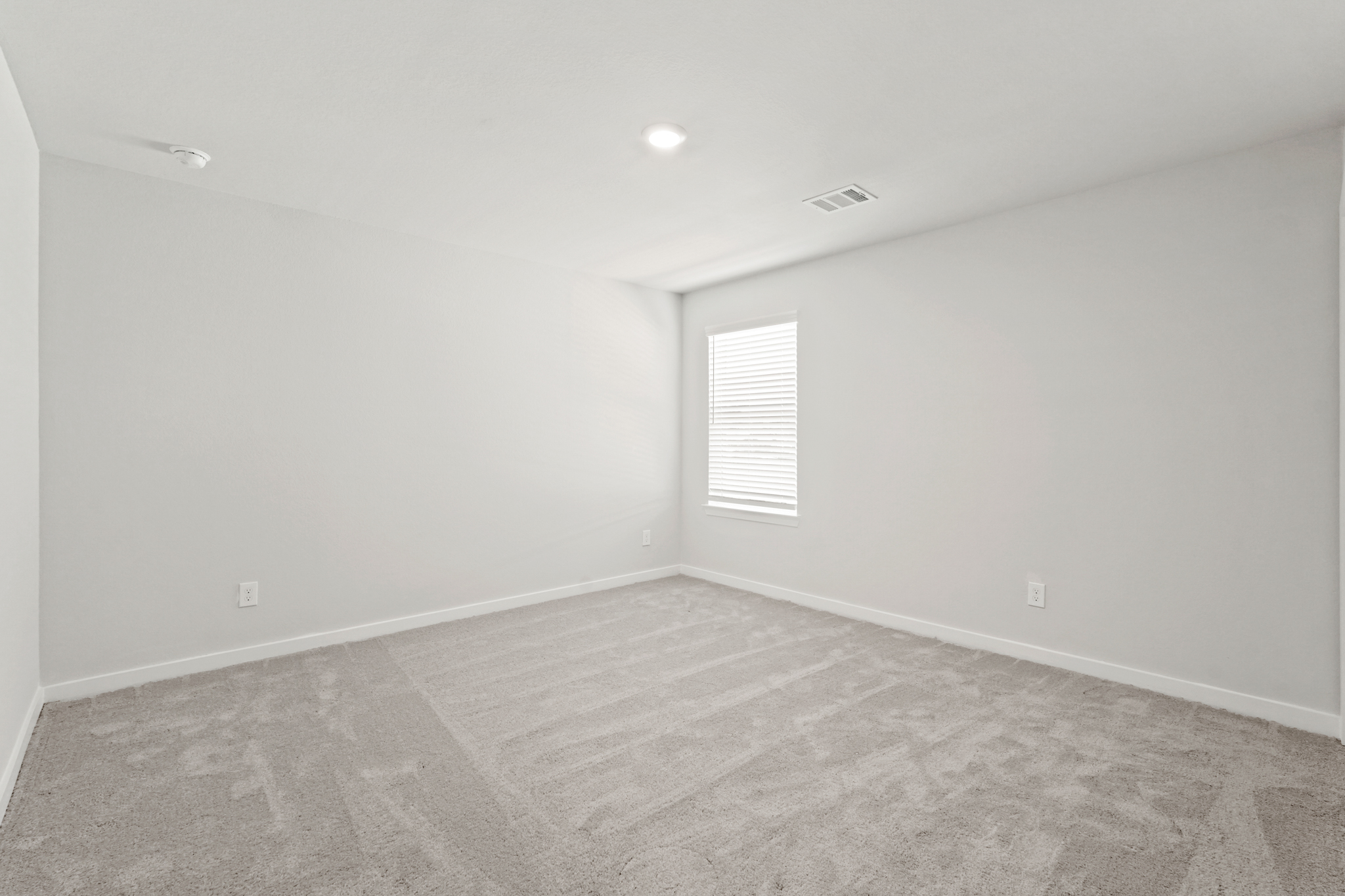 A room with a wood floor and a white wall with a window.
